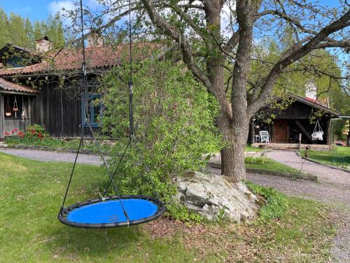 a swing in front of a house with a tree at Luftens timmerstuga in Sunne