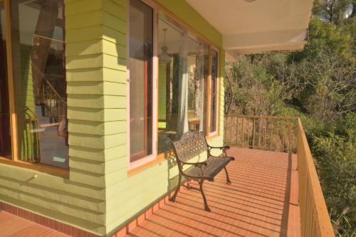 a porch of a house with a bench on it at Jaadooghar Rainbow Farms in Mussoorie