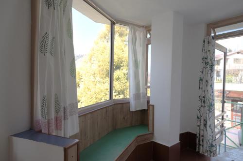 a room with two windows and a green floor at Jaadooghar Rainbow Farms in Mussoorie