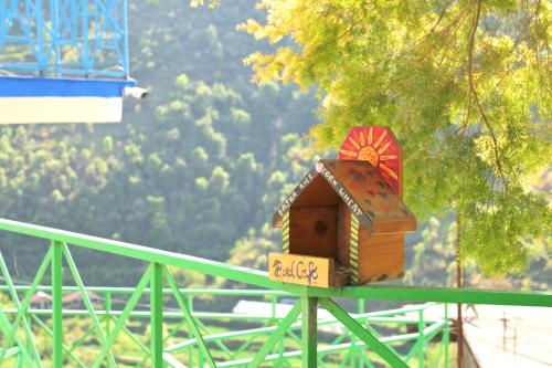 a small bird house sitting on a green rail at Jaadooghar Rainbow Farms in Mussoorie