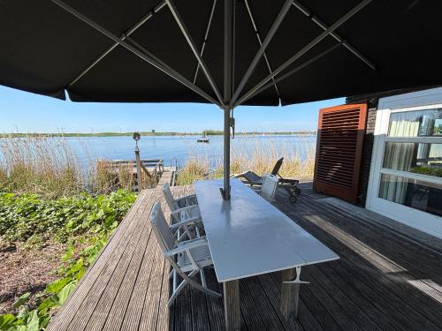 a table and chairs on a deck with an umbrella at Vakantiehuis aan De Mooie Nel in Spaarndam