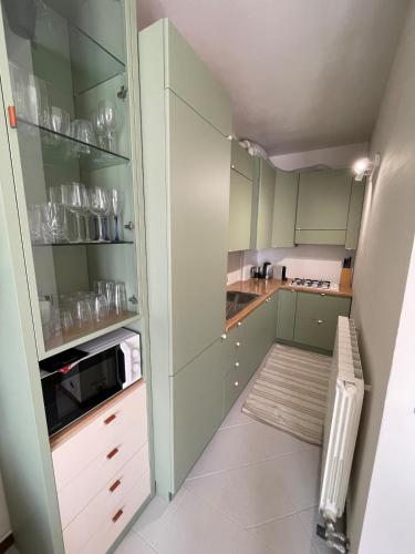 a small kitchen with green cabinets and a microwave at Lakefront Apartment with Panoramic Pool in Ranzanico