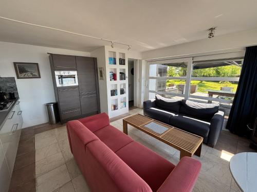 a living room with a red couch and a table at Vakantiehuis aan De Mooie Nel in Spaarndam