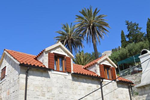 a house with a tiled roof with palm trees in the background at Apartments Lea in Hvar
