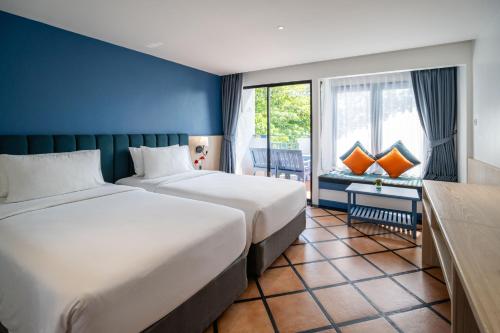 a hotel room with two beds and a window at Phuket Island View Resort - SHA Extra Plus in Karon Beach