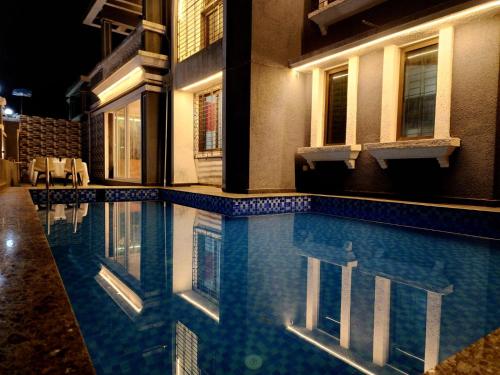 a swimming pool in front of a building at night at Twilight Stays ll VILLA 9PM II SNOOKER TAB II SWIMMING POOL ll AC II BBQ in Lonavala