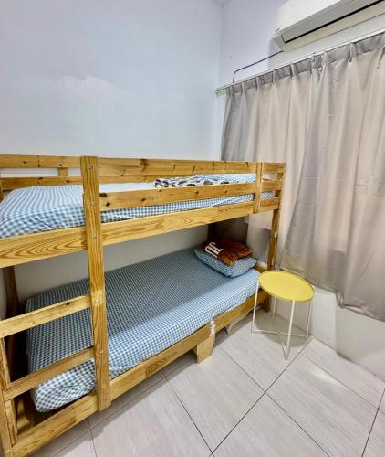 a bunk bed in a room with a table and a stool at Full Moon Apartment (月满公寓）网红 airbnb in Kuah