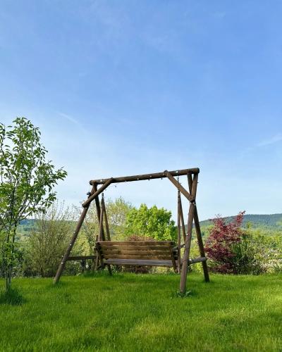 a wooden swing sitting in a field of grass at Makowy domek in Maków Podhalański