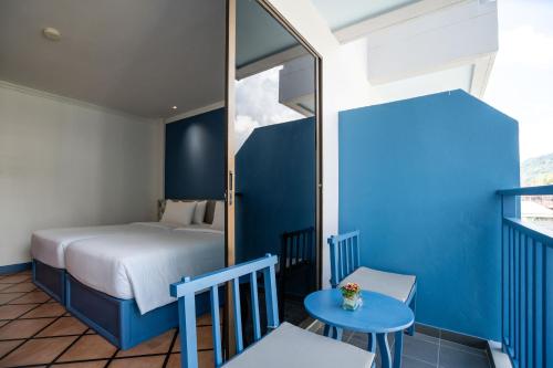 a bedroom with a bed and a blue wall at Phuket Island View Resort - SHA Extra Plus in Karon Beach