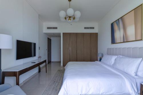 a bedroom with a bed and a desk and a television at 3BR Apartment with City and Beach Views at Address Residences Marassi in Muharraq
