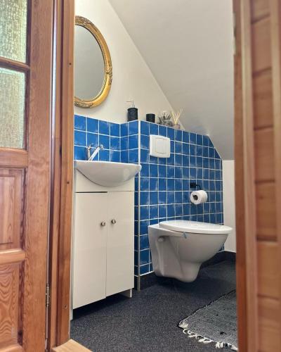 a blue tiled bathroom with a sink and a toilet at Makowy domek in Maków Podhalański
