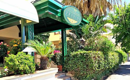 a restaurant with a green sign and some plants at Hotel Relais I Presidi in Orbetello