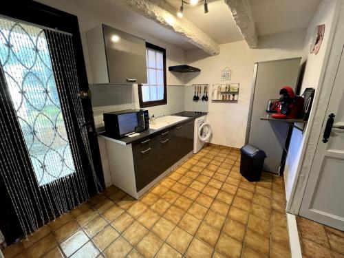 une grande cuisine avec un évier et un comptoir dans l'établissement Charmante retraite champêtre, à Bagnols-en-Forêt