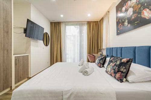 a bedroom with a large white bed and a tv at The Hotel National in Zagreb