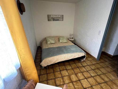 - une petite chambre avec un lit et du carrelage dans l'établissement Charmante retraite champêtre, à Bagnols-en-Forêt