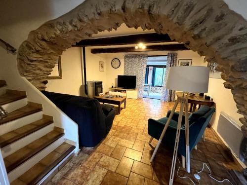 - un salon avec une arche en pierre et un canapé dans l'établissement Charmante retraite champêtre, à Bagnols-en-Forêt