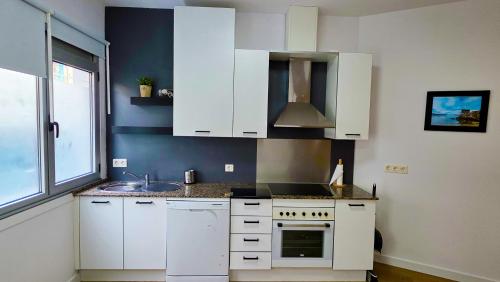 a kitchen with white cabinets and a sink at Rías Baixas Playa Vilariño, Ria de Aldan in Aldán