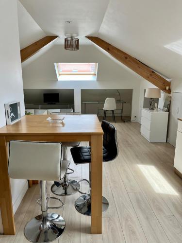 un bureau mansardé avec une table et des chaises en bois dans l'établissement Appartement atypique proche colmar, à Horbourg-Wihr