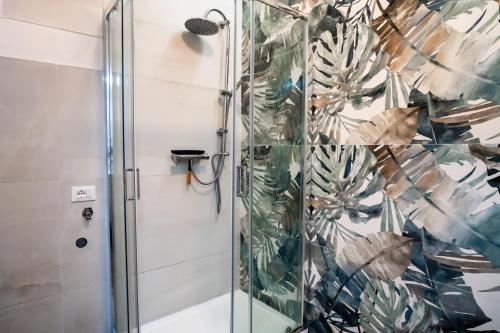 a shower with a glass door with a plant wallpaper at Zona Centralissima a 2 Passi dal Mare in Pescara