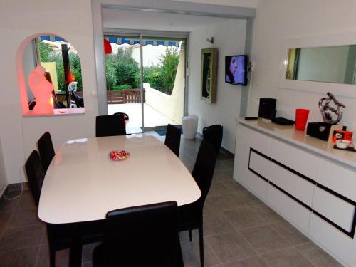 une salle à manger avec une table blanche et des chaises noires dans l'établissement Villa LA COQUINE Héliovillage 20 Luxe - 4 personnes, au Cap d'Agde