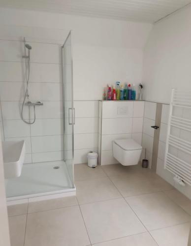 a white bathroom with a shower and a toilet at Ferienwohnung Herzberg in Loxstedt