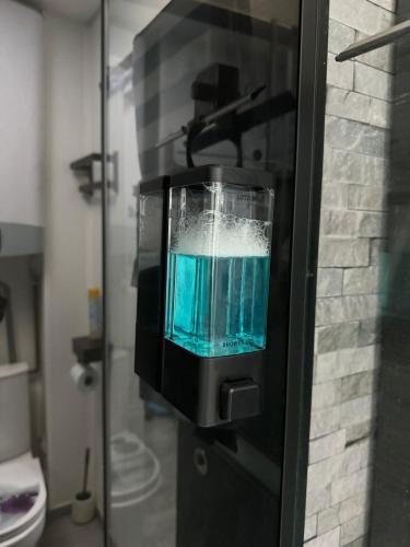 un verre de liquide bleu dans un distributeur sur un réfrigérateur dans l'établissement Gruissan Plage Studio RDC avec Piscine Wifi Parking Clim, à Gruissan