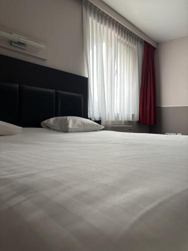 a bedroom with a white bed and a window at Hotel La Louve in La Louvière
