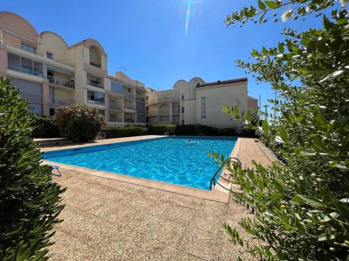 une piscine devant un immeuble dans l'établissement Gruissan Plage Studio RDC avec Piscine Wifi Parking Clim, à Gruissan
