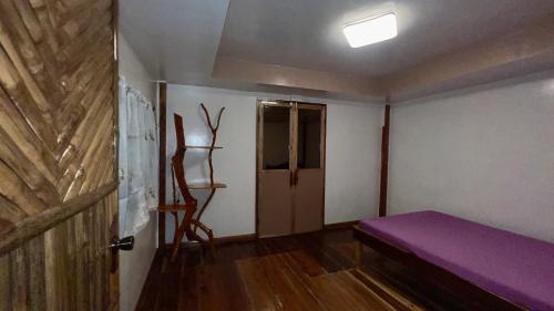 Zimmer mit einem lila Bett und einer Tür in der Unterkunft Aviniel Cottage in Puerto Galera