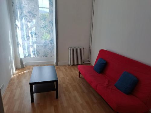 a living room with a red couch and a table at Appartement avec terrasse 53m2 in Saint-Martin-de-Valamas