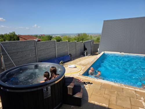 a group of people in a hot tub next to a swimming pool at Wild A-frame in Baile Felix