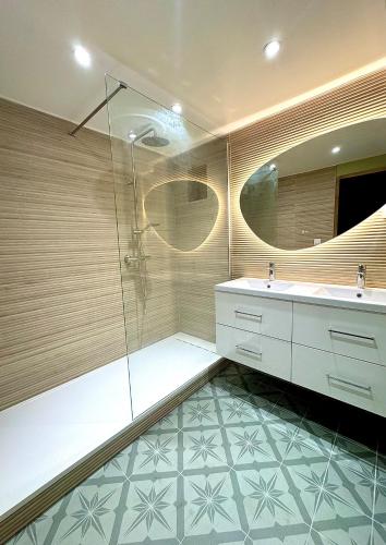 une salle de bain avec une douche, un lavabo et un miroir dans l'établissement La Cousinade de l'Esterel, à Saint-Raphaël