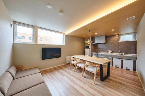 a kitchen and dining room with a table and a couch at Sauna Style Sapporo in Sapporo