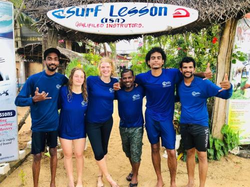 a group of people standing on the beach with a surfboard at Star Rest Surf Camp Arugambay in Arugam Bay