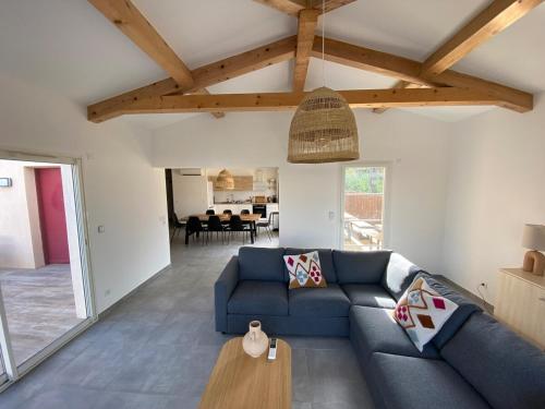 un salon avec un canapé bleu et une table dans l'établissement Ravissante villa neuve à 400 mètres des plages, à Grimaud