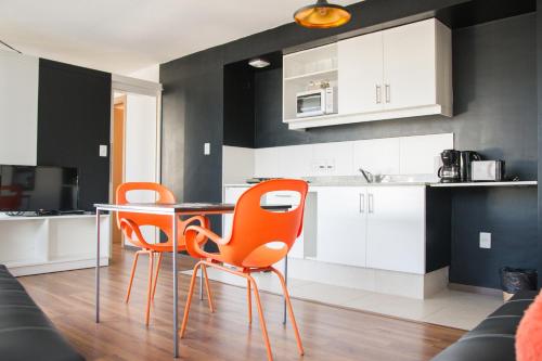 a kitchen with two orange chairs and a table at Rentline Apartamentos - Sunline in Montevideo