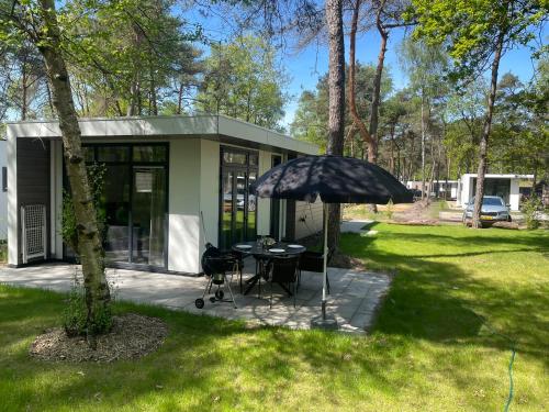 a house with a table and an umbrella in the yard at Vakantie woning "Huisje Boszicht" in Haarle