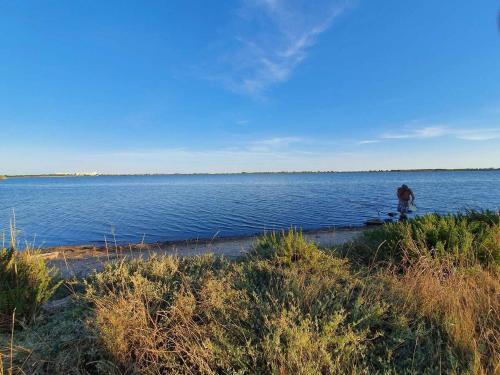 a man walking along the shore of a large body of water at La cabane des rêves in Pérols