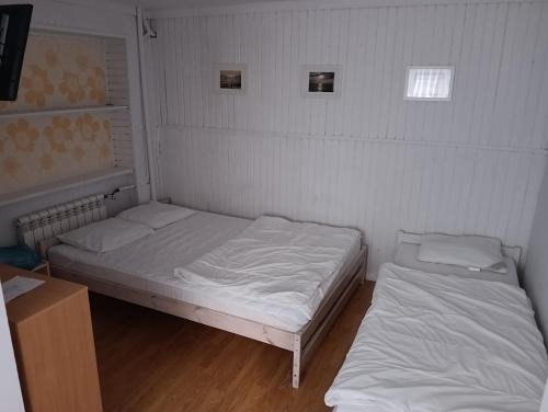 two beds in a small room with white sheets at U Jaśka in Darłówko