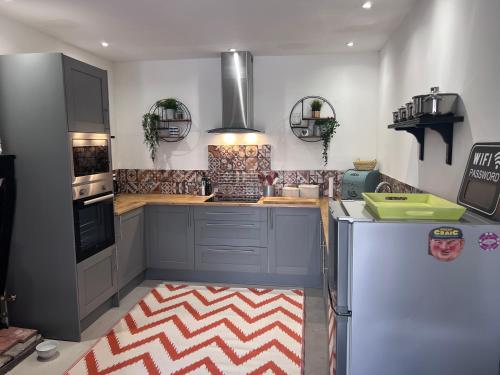 La cuisine est équipée de placards bleus et d'un réfrigérateur. dans l'établissement Atelier 9, à LʼIsle-Jourdain