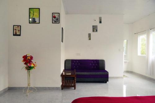 a living room with a purple couch and a vase of flowers at Wilderstay Resort in Meppādi