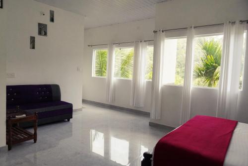 a bedroom with a bed and a couch and windows at Wilderstay Resort in Meppādi