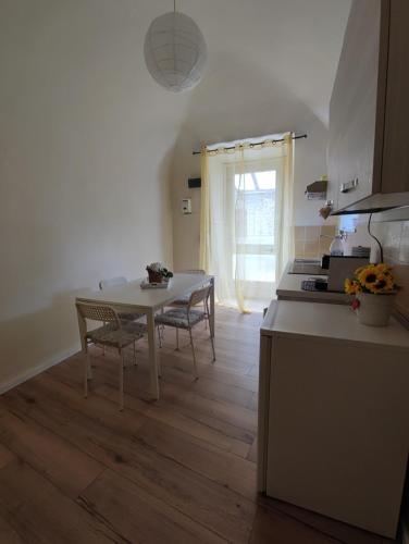a kitchen with a white table and chairs and a table and a table and chairs at La casina nel borgo in Volterra