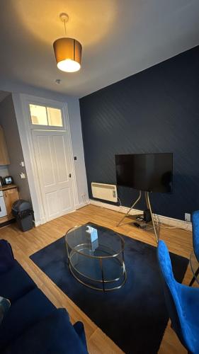 a living room with a tv and a glass table at Homely in Hampden in Glasgow