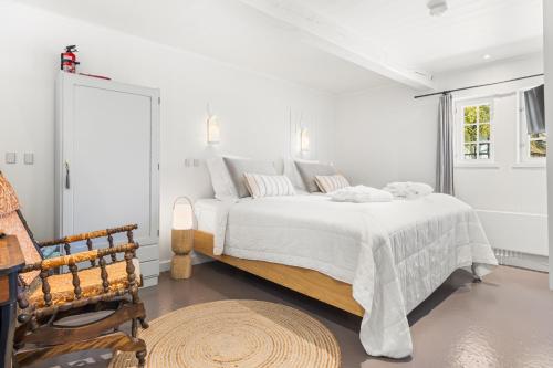 a white bedroom with a bed and a chair at Solbjerggaard Bed & Breakfast in Fåborg