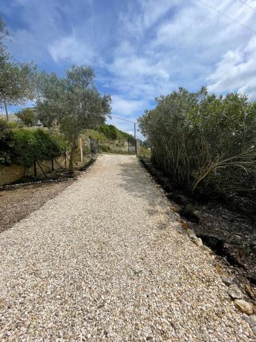 a gravel road with trees and bushes on the side at Les Oliviers Villa with Sea view on Petani Beach in Vovikes