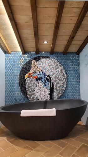 a black bath tub with a mosaic wall at La Torre sulla via Francigena in Gambassi Terme