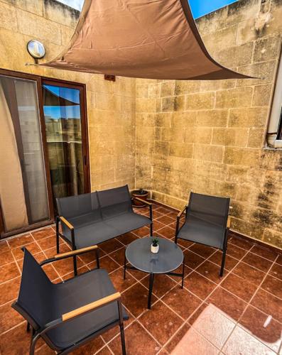 a patio with chairs and tables and a tent at Iz-Ziffa Penthouse - Hosted by Encanto Gozo in Qala