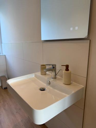 a white sink in a bathroom with a mirror at 3-Zimmer-Wohnung in Hamburg am Flughafen in Hamburg