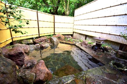 a small pond with a table and a fence at Akasawa Onsen Ryokan in Nasushiobara